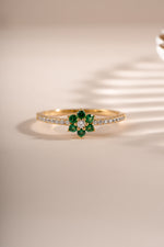 Gold ring featuring an emerald flower design by Sami Jewels, showcasing a detailed emerald gemstone flower on a sleek gold band.