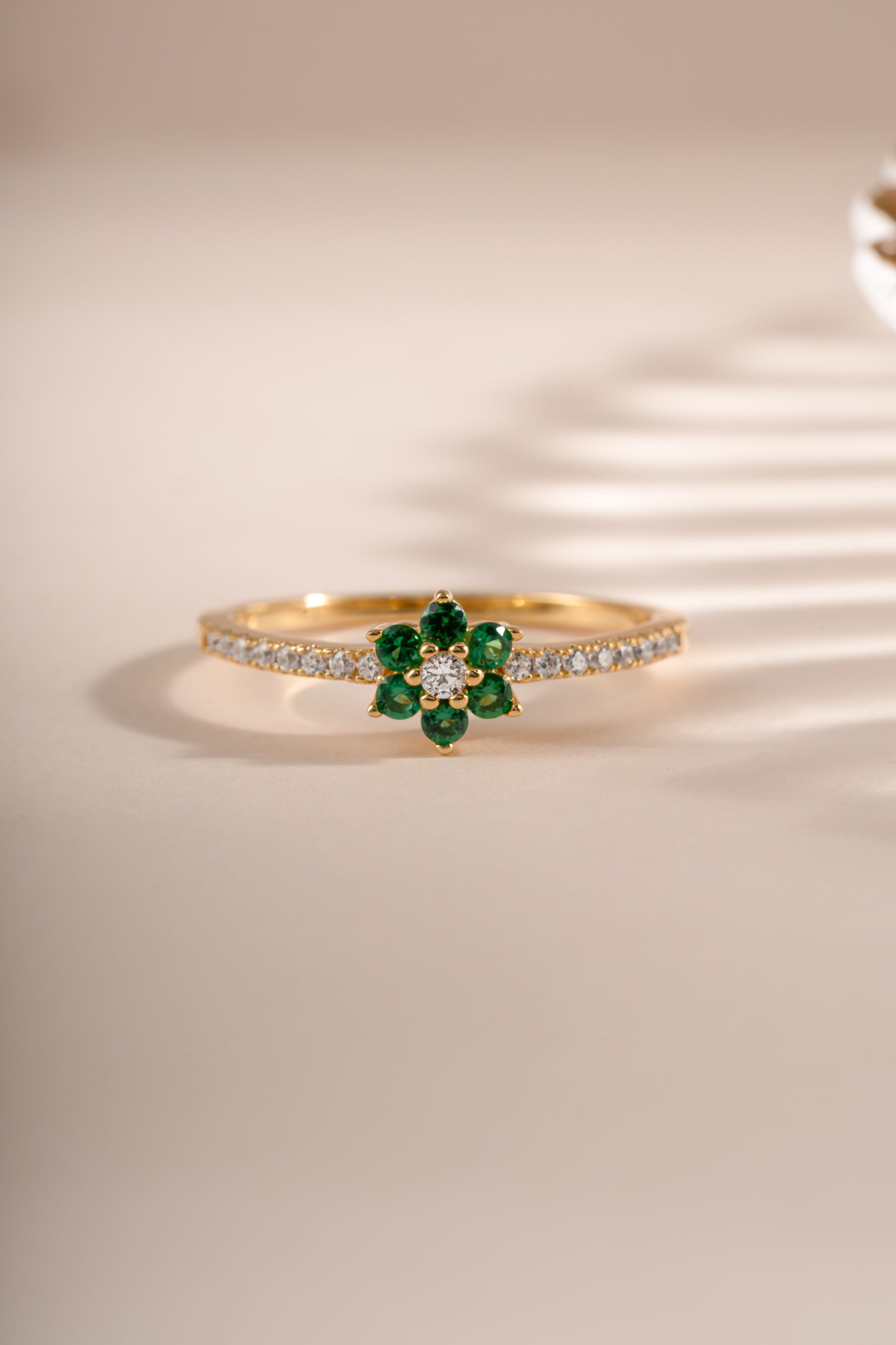 Gold ring featuring an emerald flower design by Sami Jewels, showcasing a detailed emerald gemstone flower on a sleek gold band.