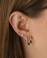 Gold emerald hoop earrings from Sami Jewels, featuring vibrant green gemstones in a classic hoop design.