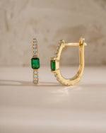 Gold emerald hoop earrings from Sami Jewels, side view showcasing round green emeralds set in hoop design.