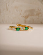 Gold hoop earrings with emerald stones from Sami Jewels, showcasing a detailed and elegant jewelry design.