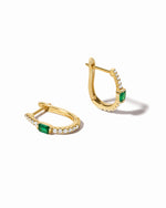 Gold emerald hoop earrings by Sami Jewels featuring vibrant green gemstones on a white background.