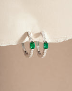 Close-up of Sami Jewels emerald hoop earrings made of sterling silver, showcasing vibrant green gemstones and sleek hoop design.