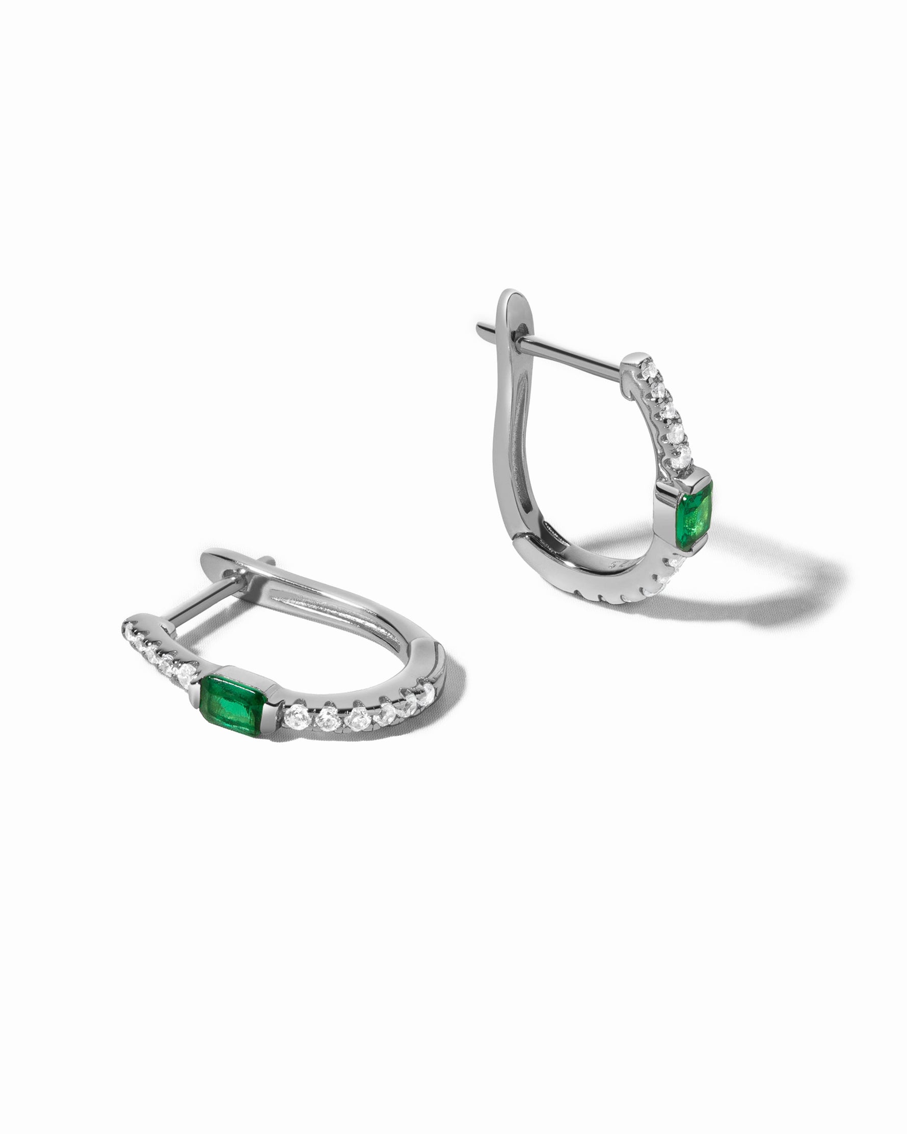 Sterling silver emerald hoop earrings by Sami Jewels, featuring vibrant green gemstones on a white background.