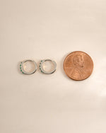 Sterling silver 7mm emerald huggie earrings with side profile view, showcasing the vibrant green gemstones and sleek design.