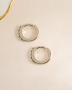 Sterling silver 7mm emerald huggie earrings with side view, showcasing the vibrant green gemstones and sleek design.