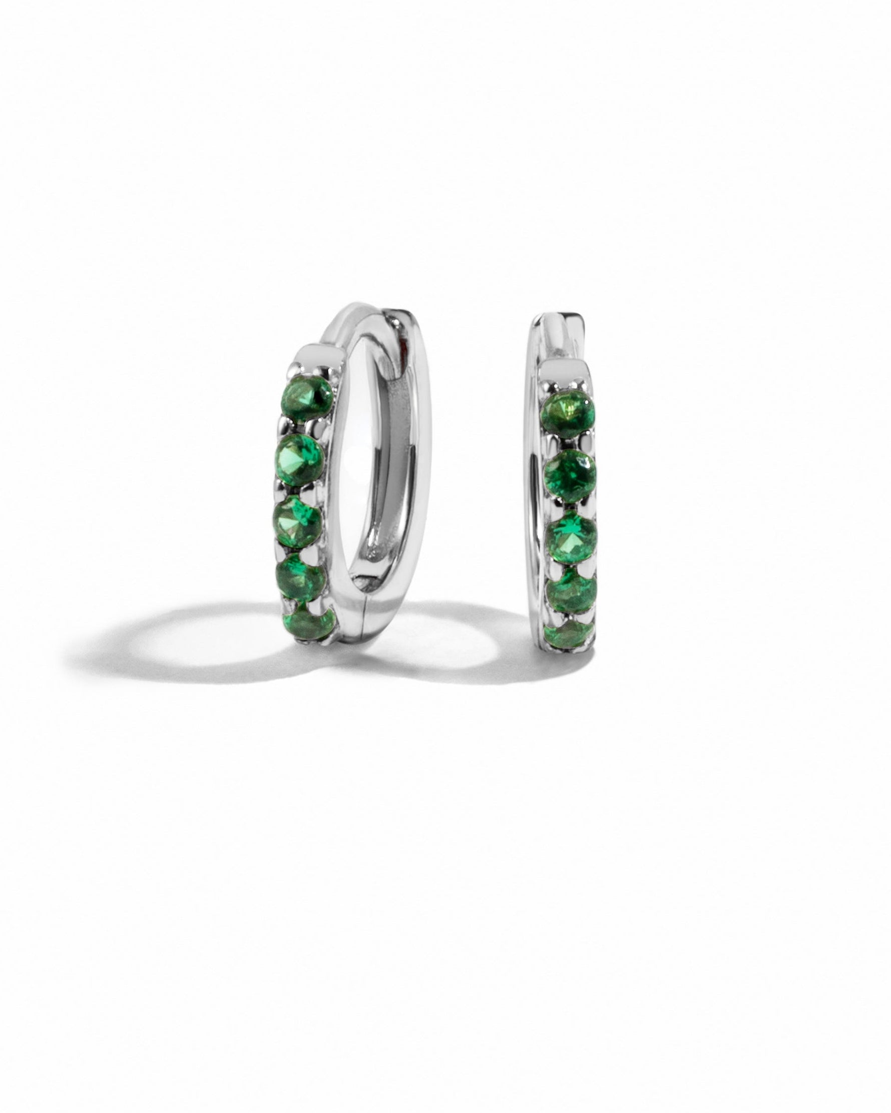 Sterling silver 7mm emerald huggie earrings with vibrant green gemstones, showcasing elegant jewelry design.