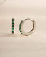 Sterling silver 7mm emerald huggie earrings featuring vibrant green gemstones, designed for a stylish and comfortable fit.