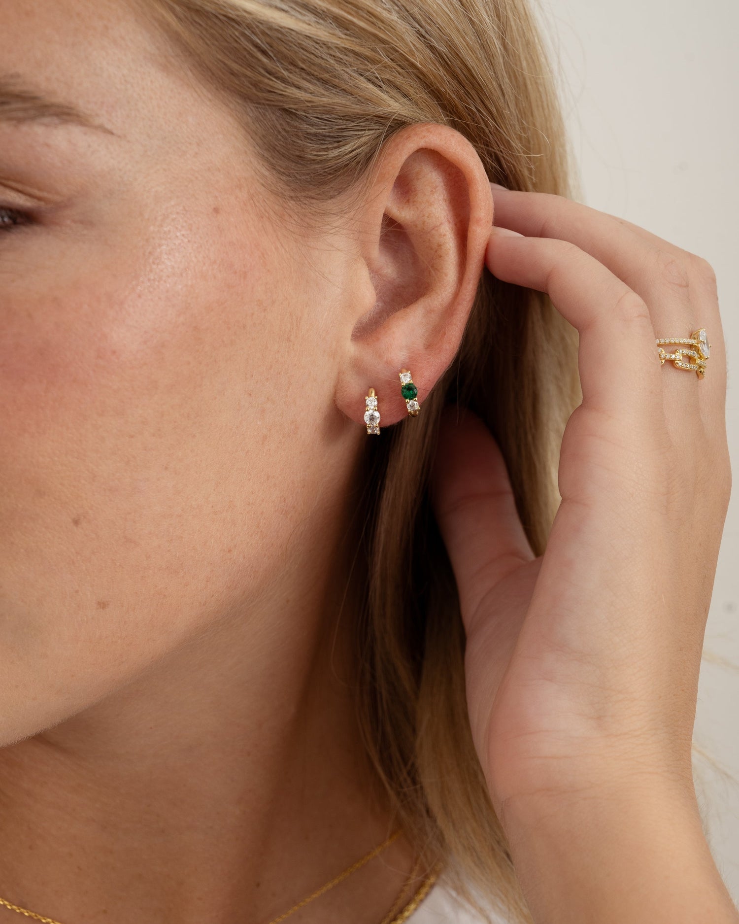 emerald three stone huggie hoop earring in gold on models ear