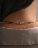 Close view of gold emerald tennis necklace on model