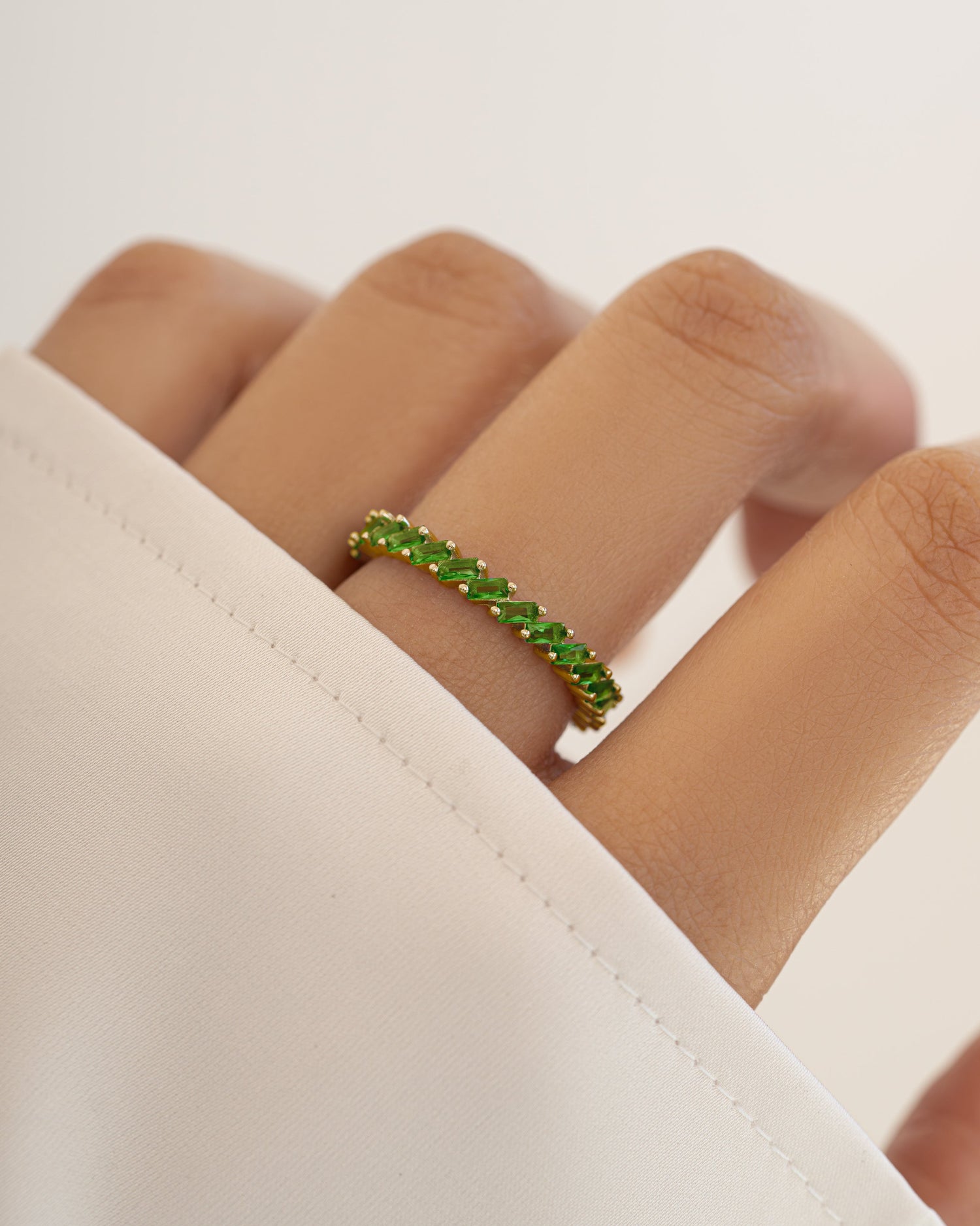 Gold Sami Jewels slanted emerald baguette ring featuring a sleek, modern design with a prominent emerald gemstone.