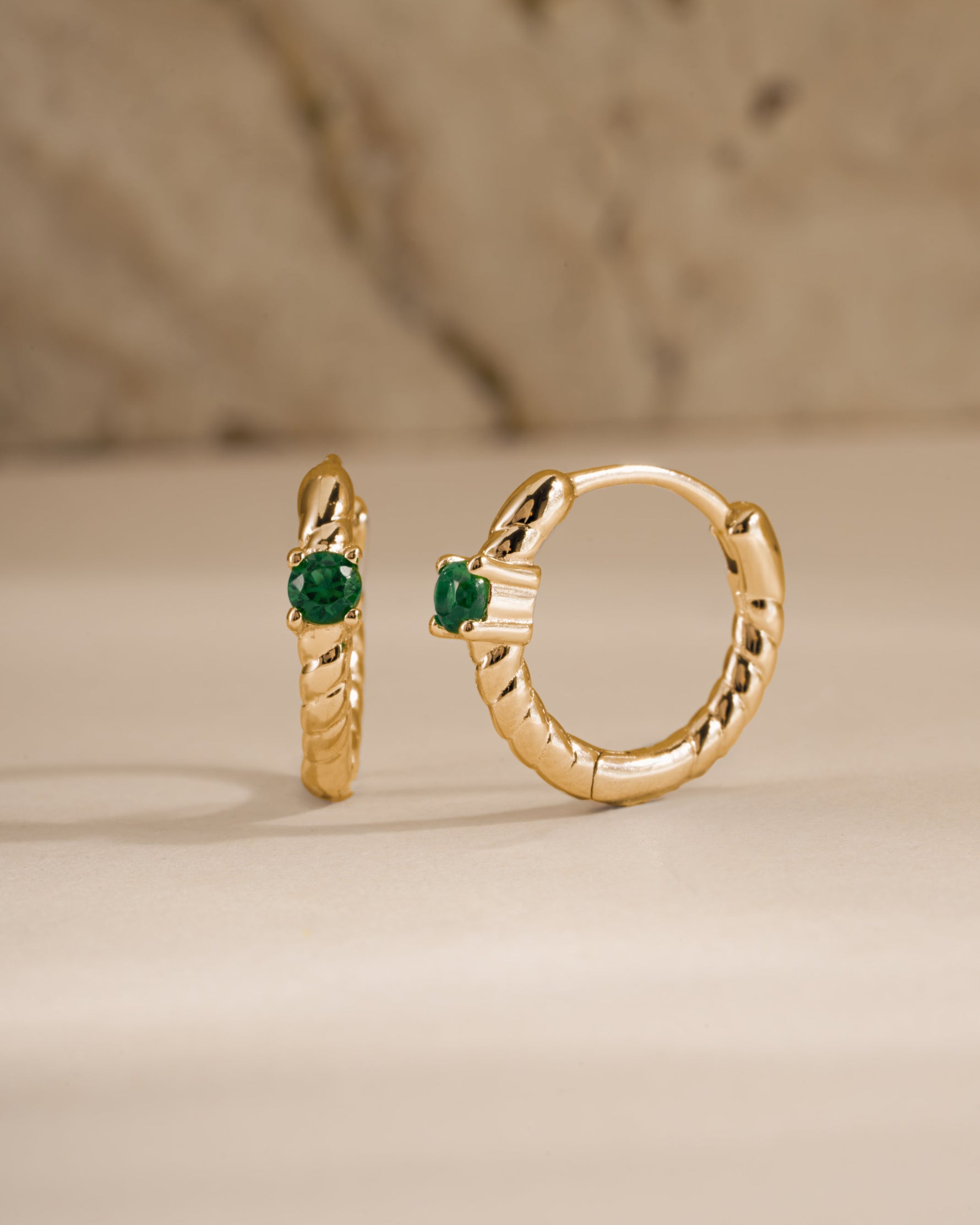 emerald spiral huggies in gold angled view