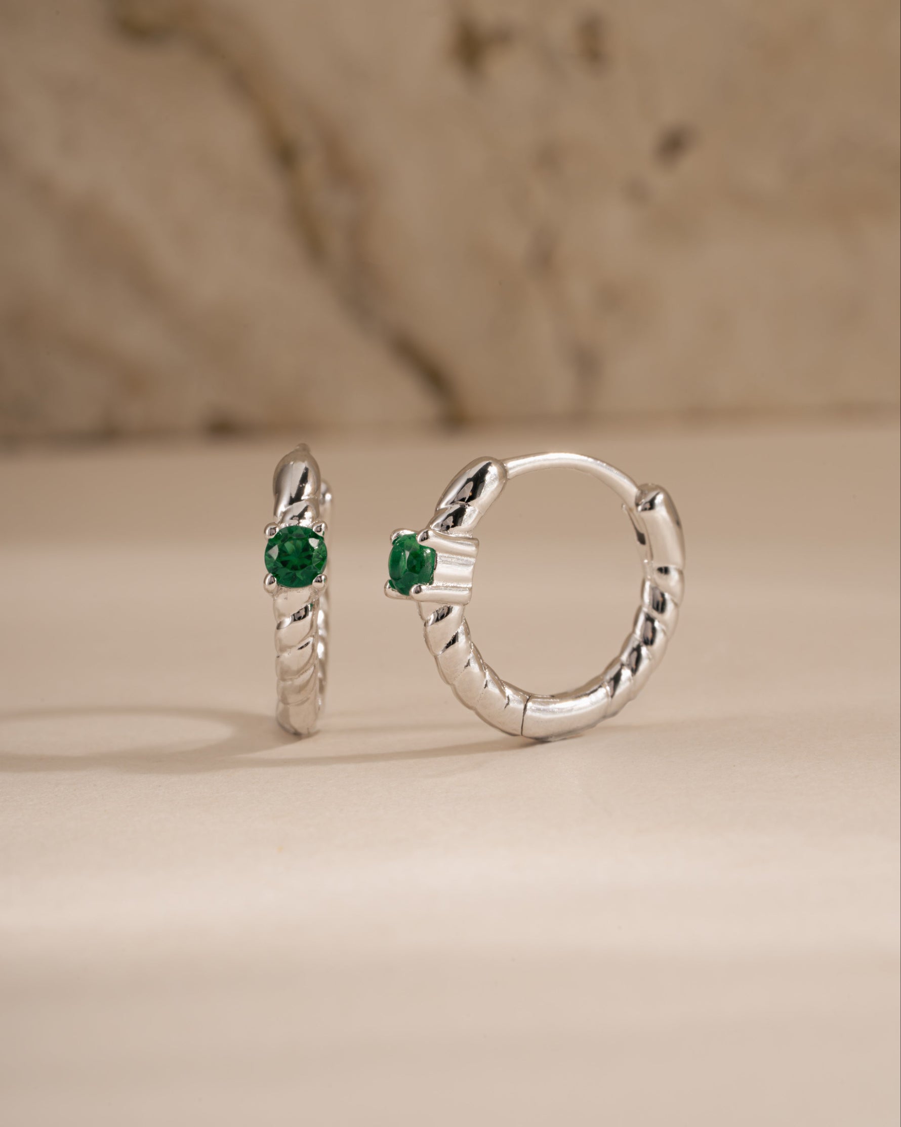emerald spiral huggies in sterling silver angled view