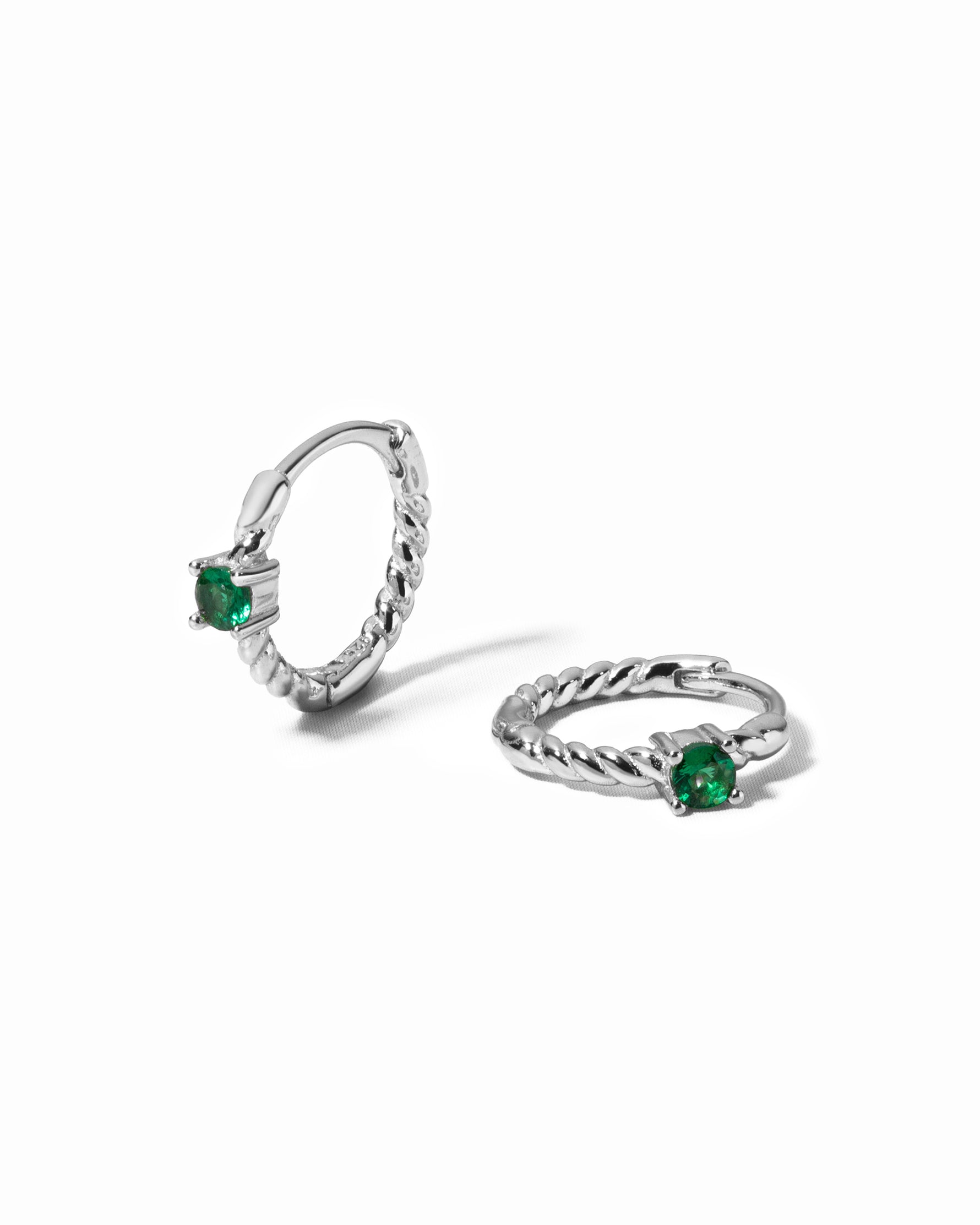 emerald spiral huggies in sterling silver on white background