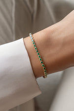 Model wearing gold emerald bezel tennis bracelet on wrist