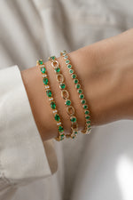Emerald bezel tennis bracelet stacked with gold bracelets