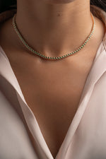 Model wearing gold round emerald tennis necklace