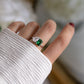 model's hand wearing a silver emerald ring that is a toi et moi style