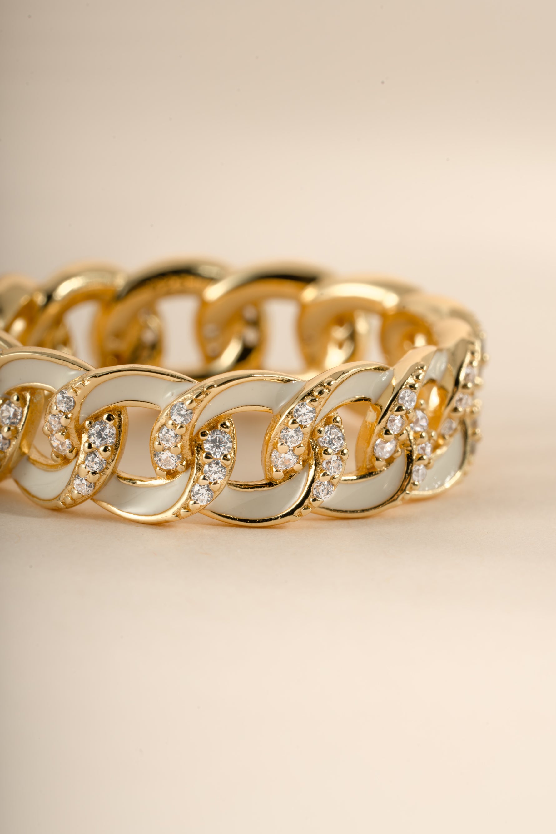 Close-up of a white enamel chain ring by Sami Jewels, showcasing the detailed white enamel design and gold chain accents.