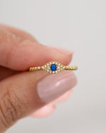 adjustable evil eye ring in gold held between two fingers