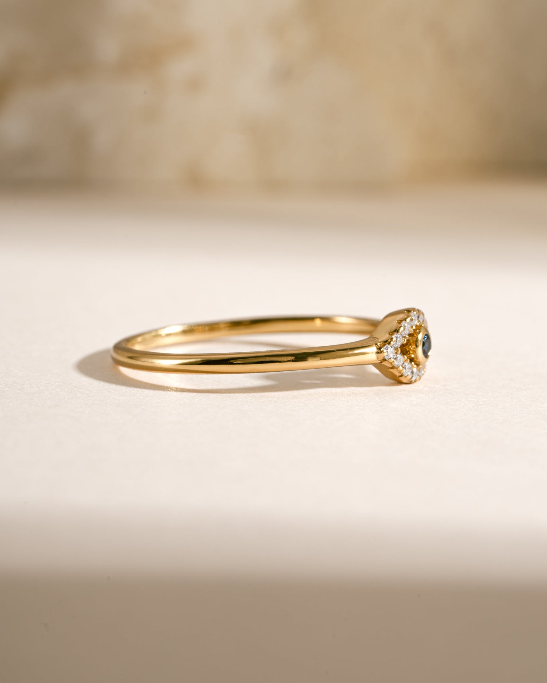 Side view of Samijewels-527 tiny blue evil eye ring in gold, showcasing its delicate design and detailed evil eye charm.