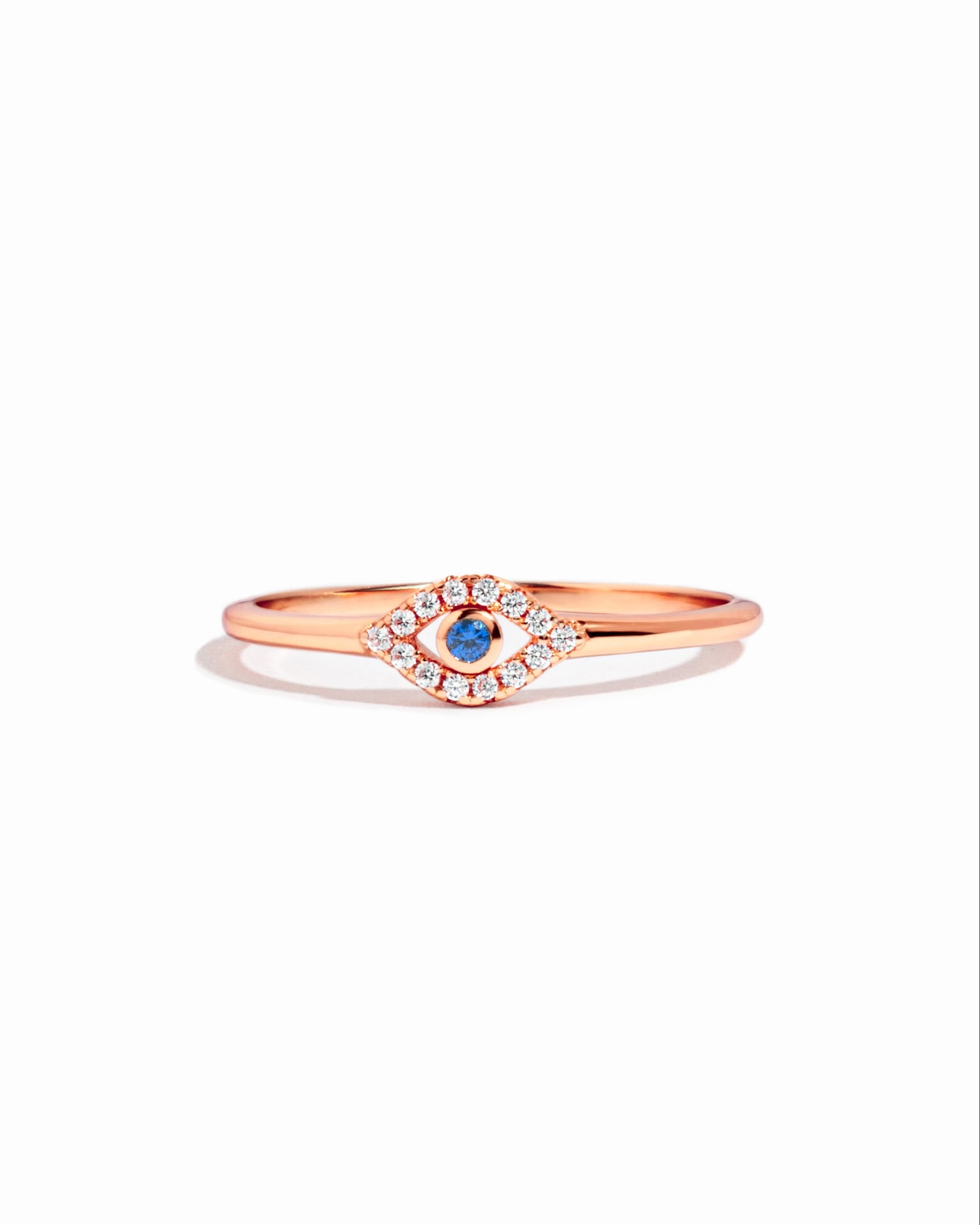 Tiny blue evil eye ring by Samijewels-527 featuring a rose gold band and a small blue evil eye charm against a white background.