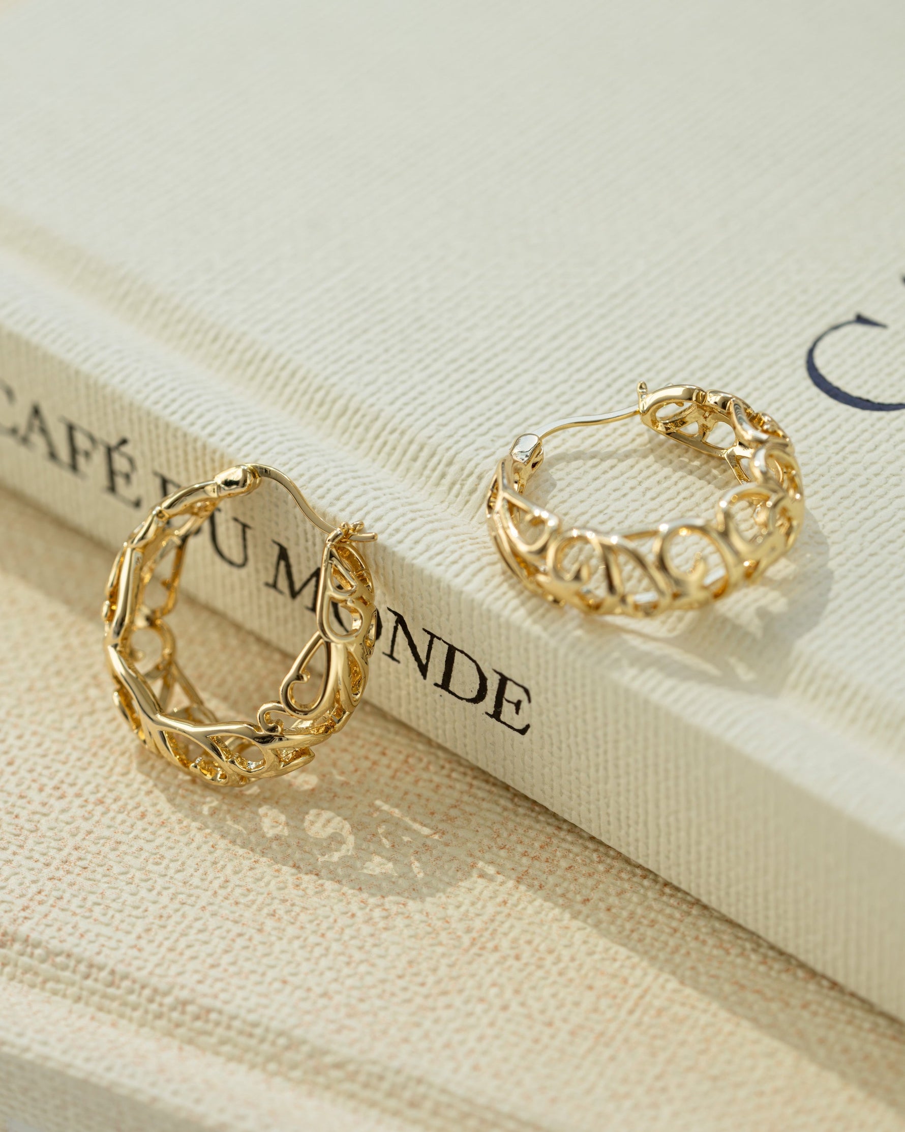 Gold filigree tapered hoop earrings by Sami Jewels showing intricate lace-like metalwork and a tapered design.