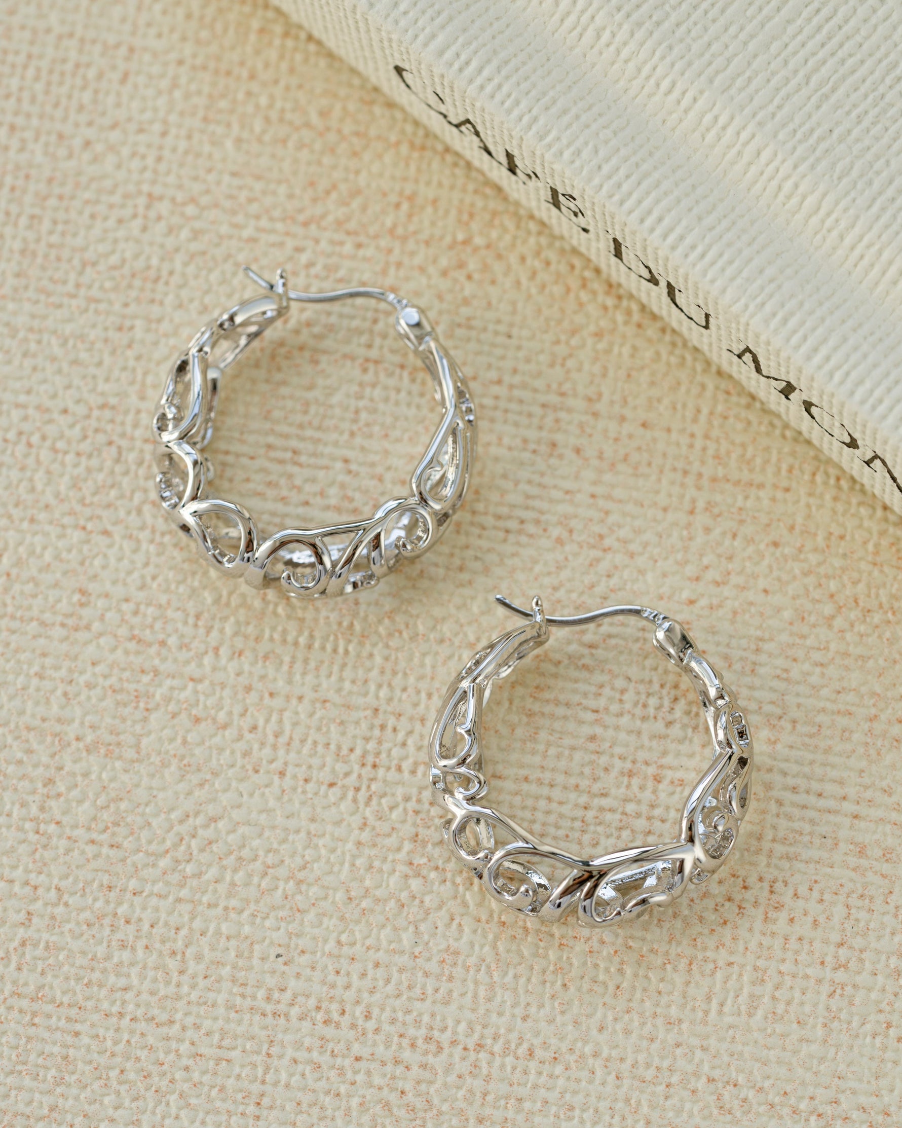 Silver filigree tapered hoop earrings by Sami Jewels worn on a model, showcasing intricate openwork design.