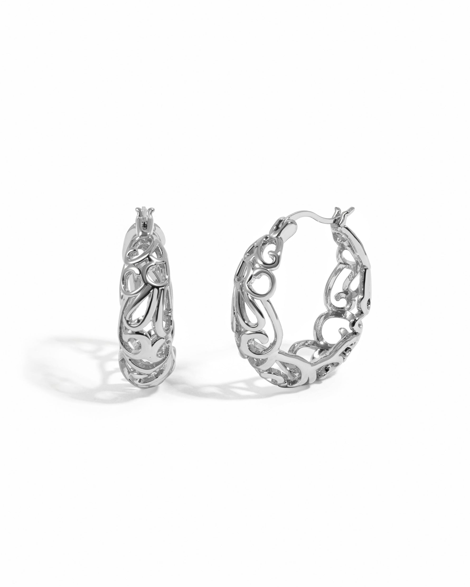 Silver filigree tapered hoop earrings by Sami Jewels on a white background.