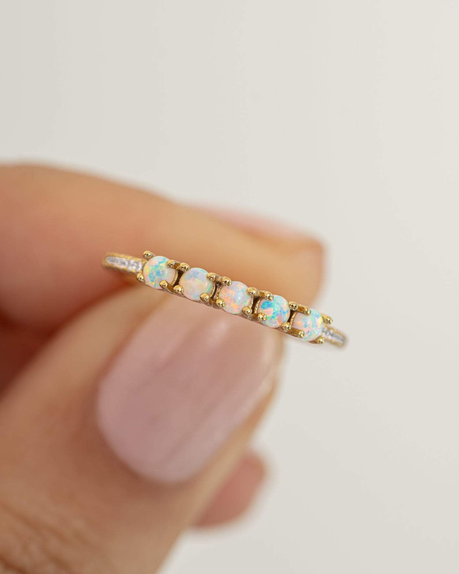 Close-up of Samijewels-527 five-stone opal ring with gold band, showcasing vibrant multi-colored opal stones and intricate detailing.