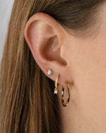 Gold 18mm flat hoop earrings by Sami Jewels, showing shiny round earrings worn by a model.