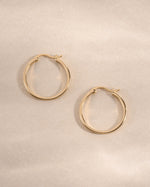 Gold 18mm flat hoop earrings by Sami Jewels featuring sleek, minimalist design with smooth, shiny surface.