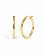 Gold 18mm flat hoop earrings from Sami Jewels displayed on a white background.