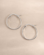 Sterling silver 18mm flat hoop earrings by Sami Jewels, showcasing sleek, minimalist design and polished surface.