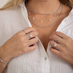 Delicate Diamond Flower Necklace layered on model, perfect for every outfit. Silver necklaces layered with diamond flower necklace and paperclip necklaces.