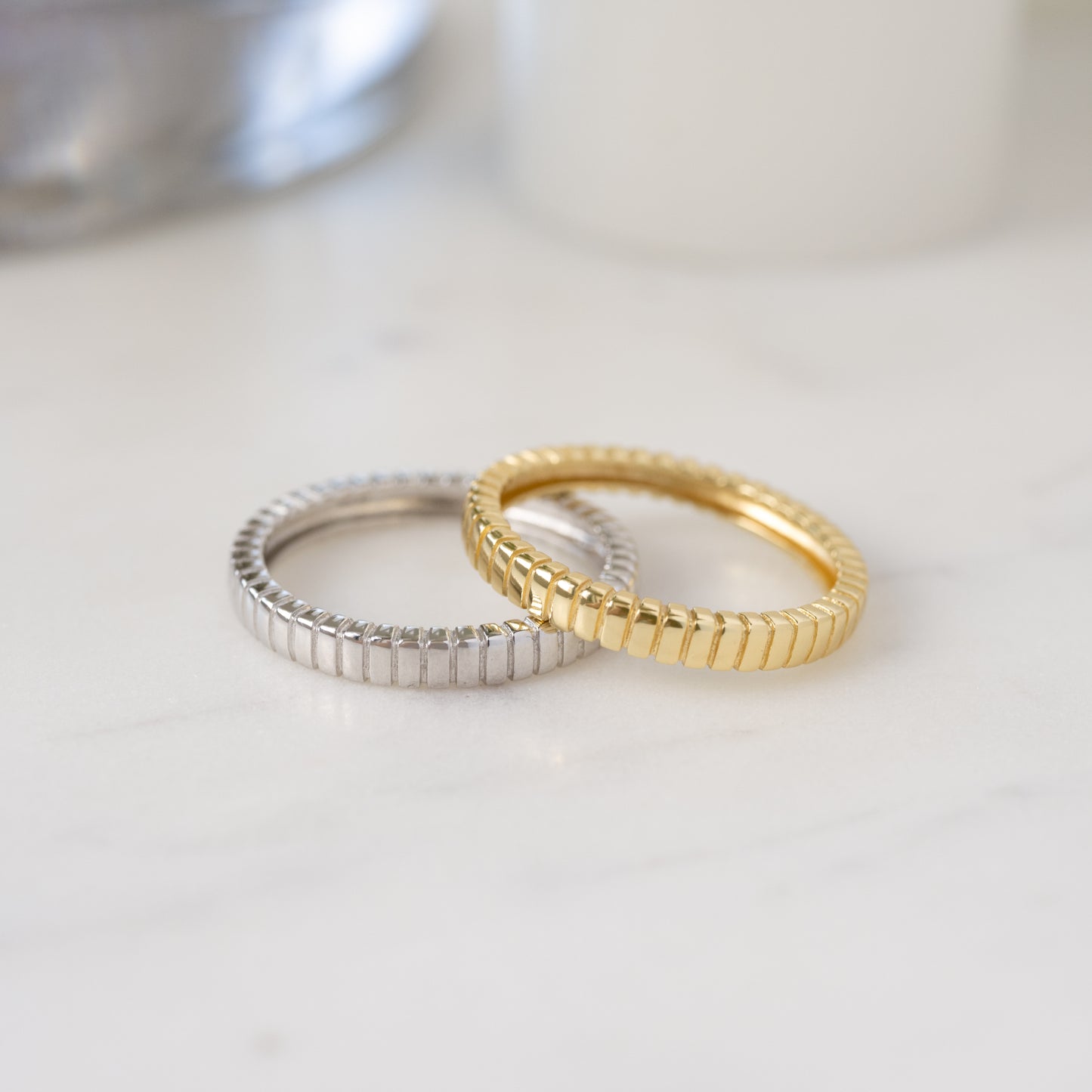 gold fluted stacking ring resting on top of sterling silver fluted stacking ring