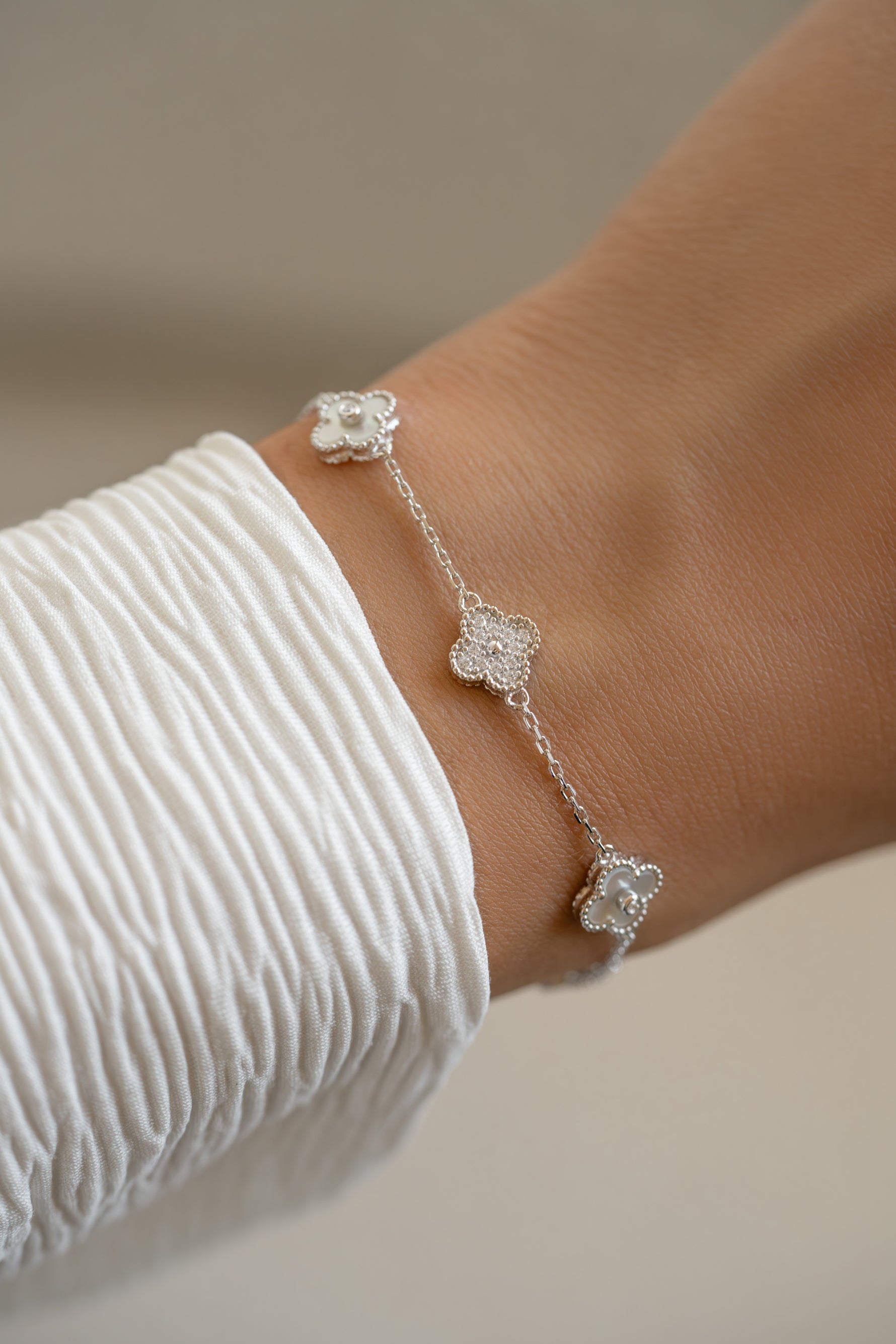 Sterling silver Sami Jewels four-leaf clover bracelet with diamond accents on a wrist, showcasing detailed leaf design and rhodium finish.