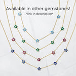 multiple colors gemstone flower necklaces from Sami Jewels on white background. Blue, emerald green, ruby red and sapphire blue flower diamond pendants on thin dainty chain.