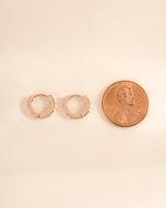 Rose gold geometric pattern huggie earrings by Sami Jewels, shown in a side profile view.