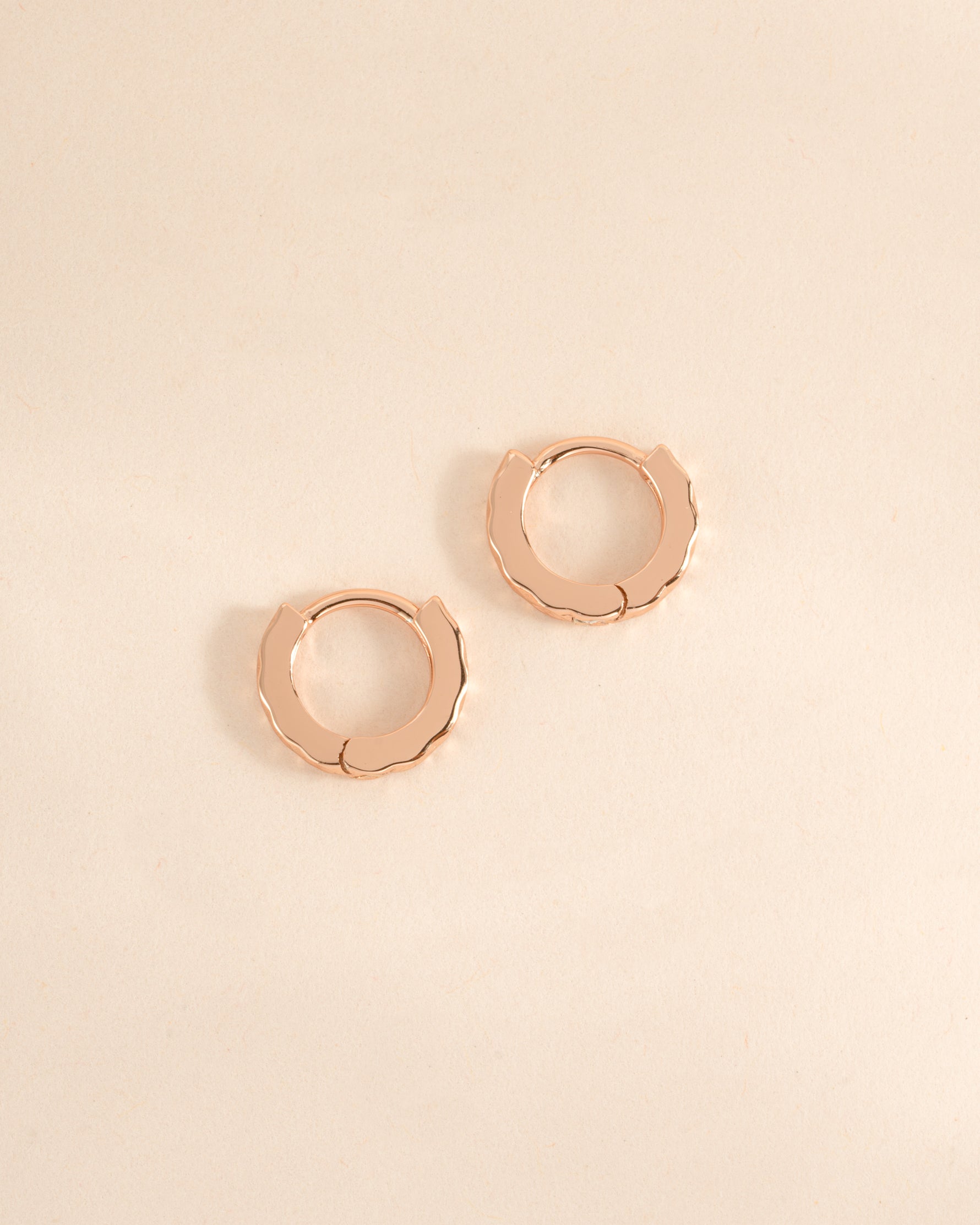 Rose gold Sami Jewels geometric pattern huggie earrings shown from a side view with intricate design.