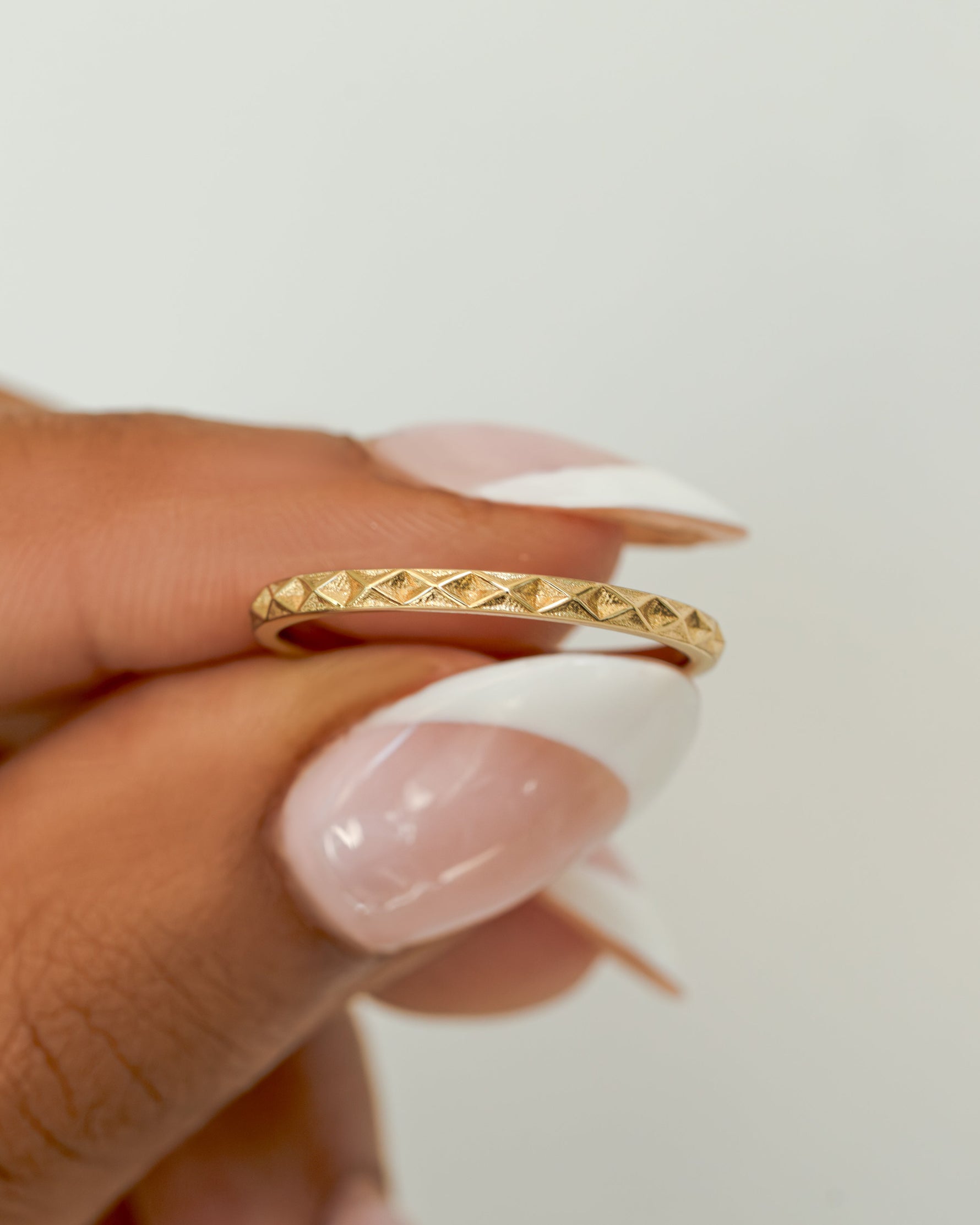 geometric stacking ring in gold held between fingers 