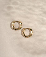 gold 10mm hoop earrings on a neutral background