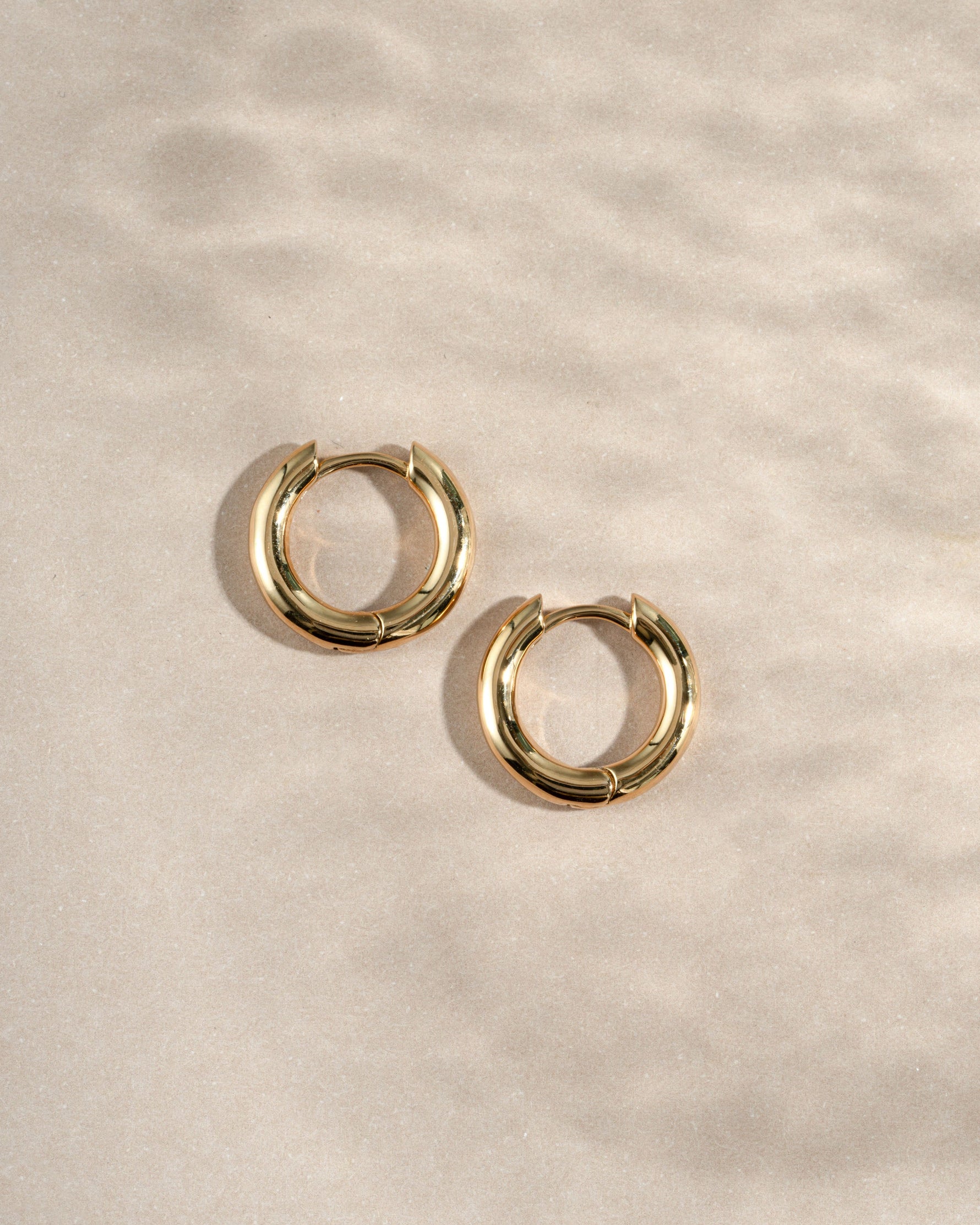 gold 10mm hoop earrings on a neutral background