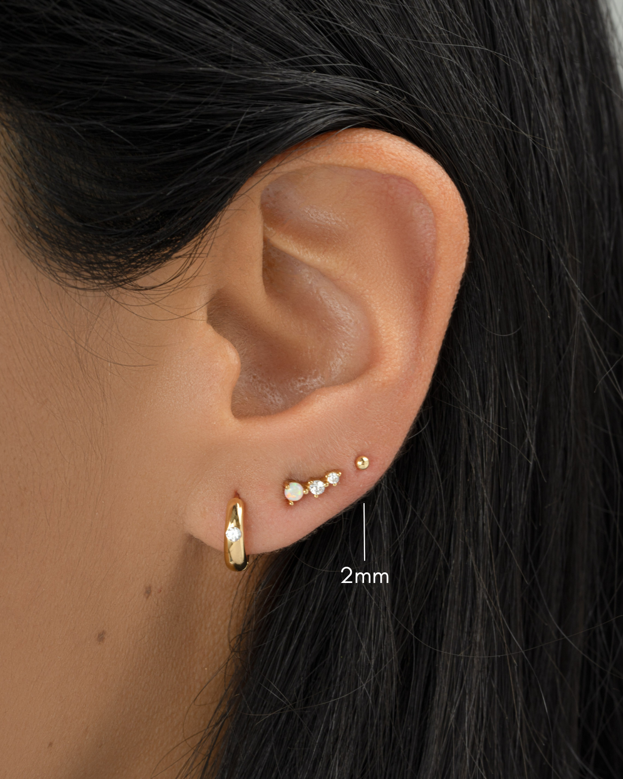 gold 2mm ball stud earring as third hole ear piercing on womens ear
