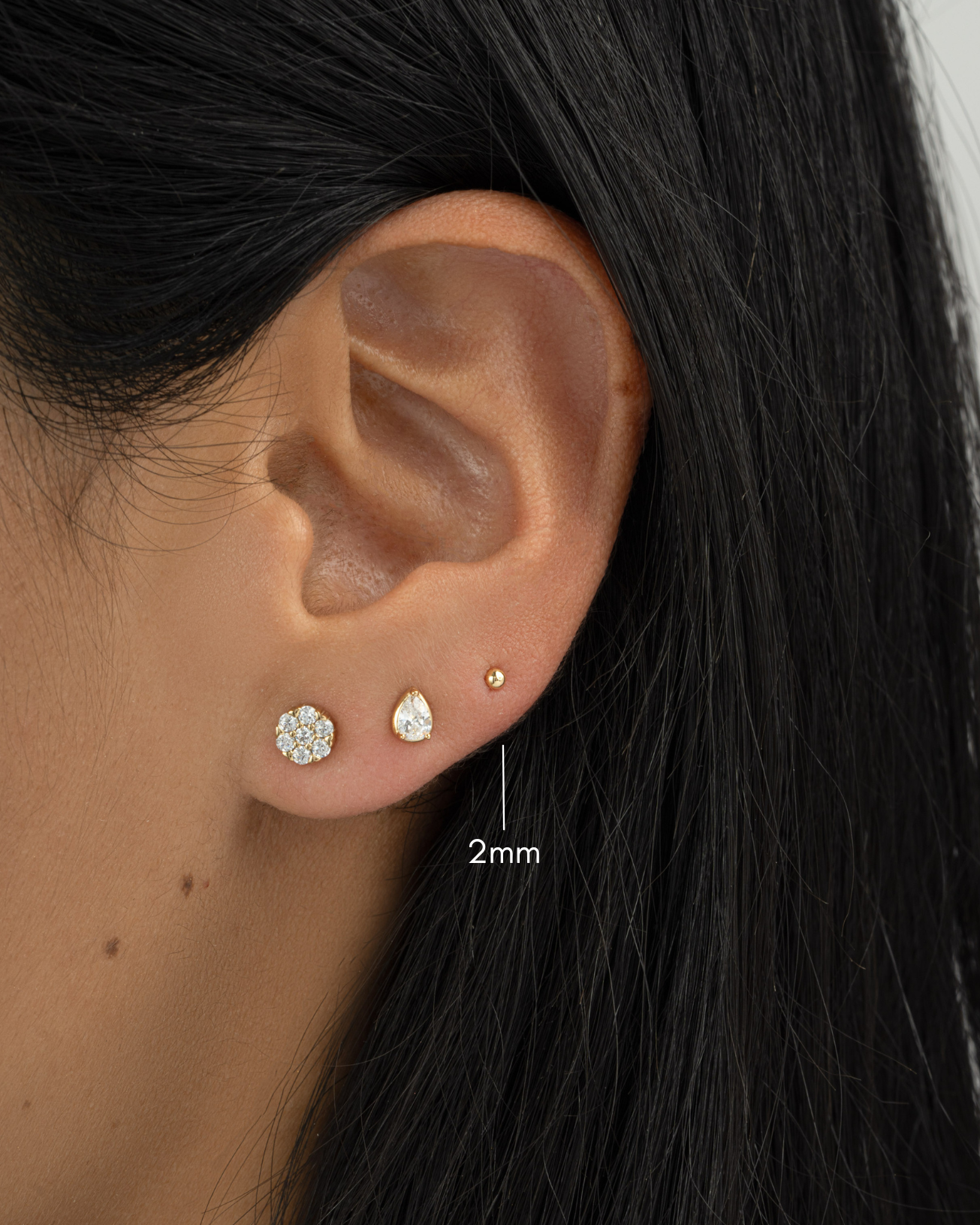 gold 2mm ball stud earring stack closeup on womens ear
