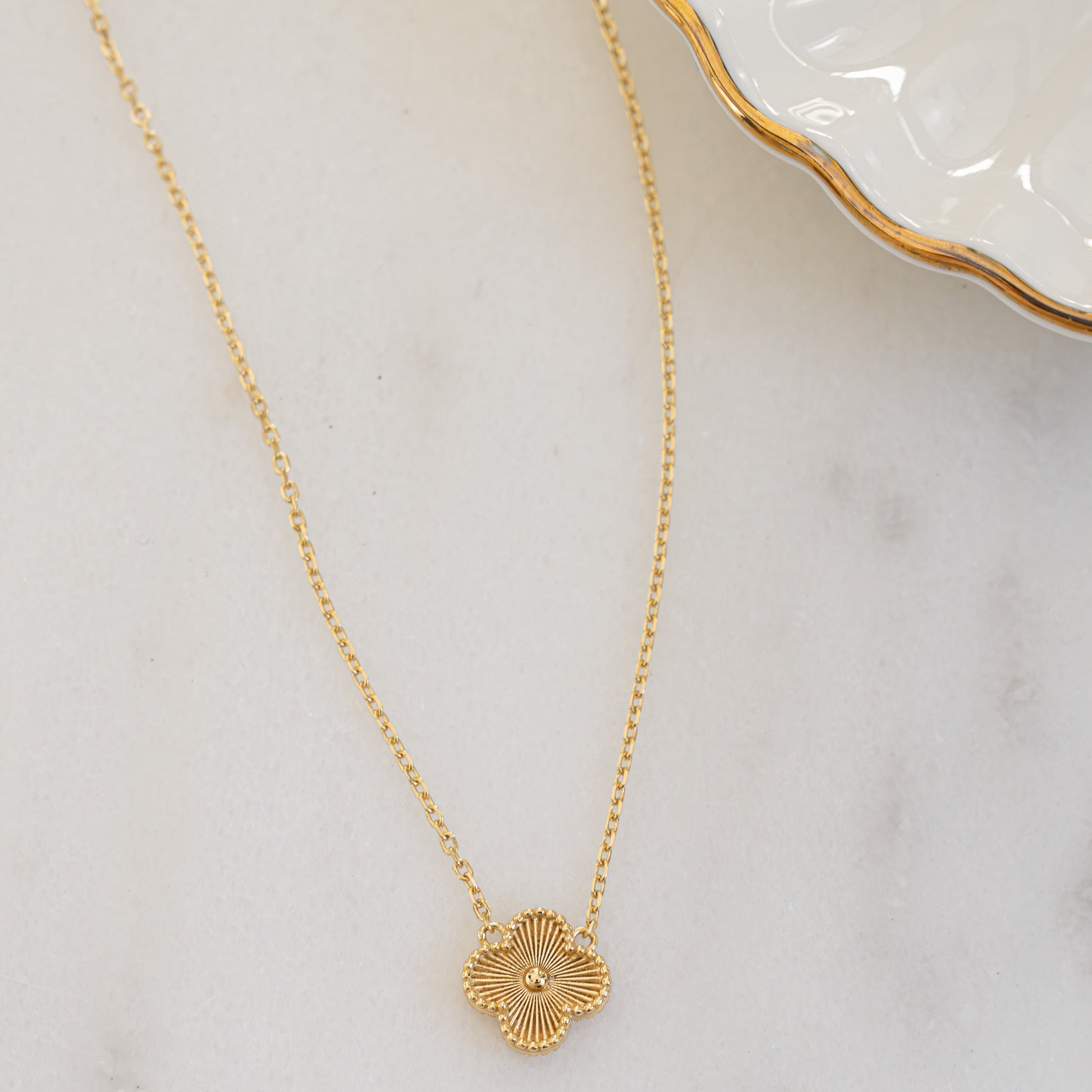 Close-up of gold four leaf clover necklace with intricate design