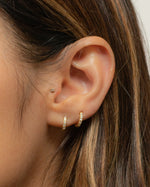 Women wearing gold 7mm diamond huggie earring in her first and second hole ear piercing