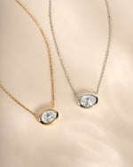 Gold and silver east-west oval CZ bezel necklaces shown side by side.