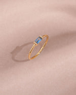 Gold aquamarine baguette ring with diamond accents, close-up view showcasing elegant design and sparkling gemstones.