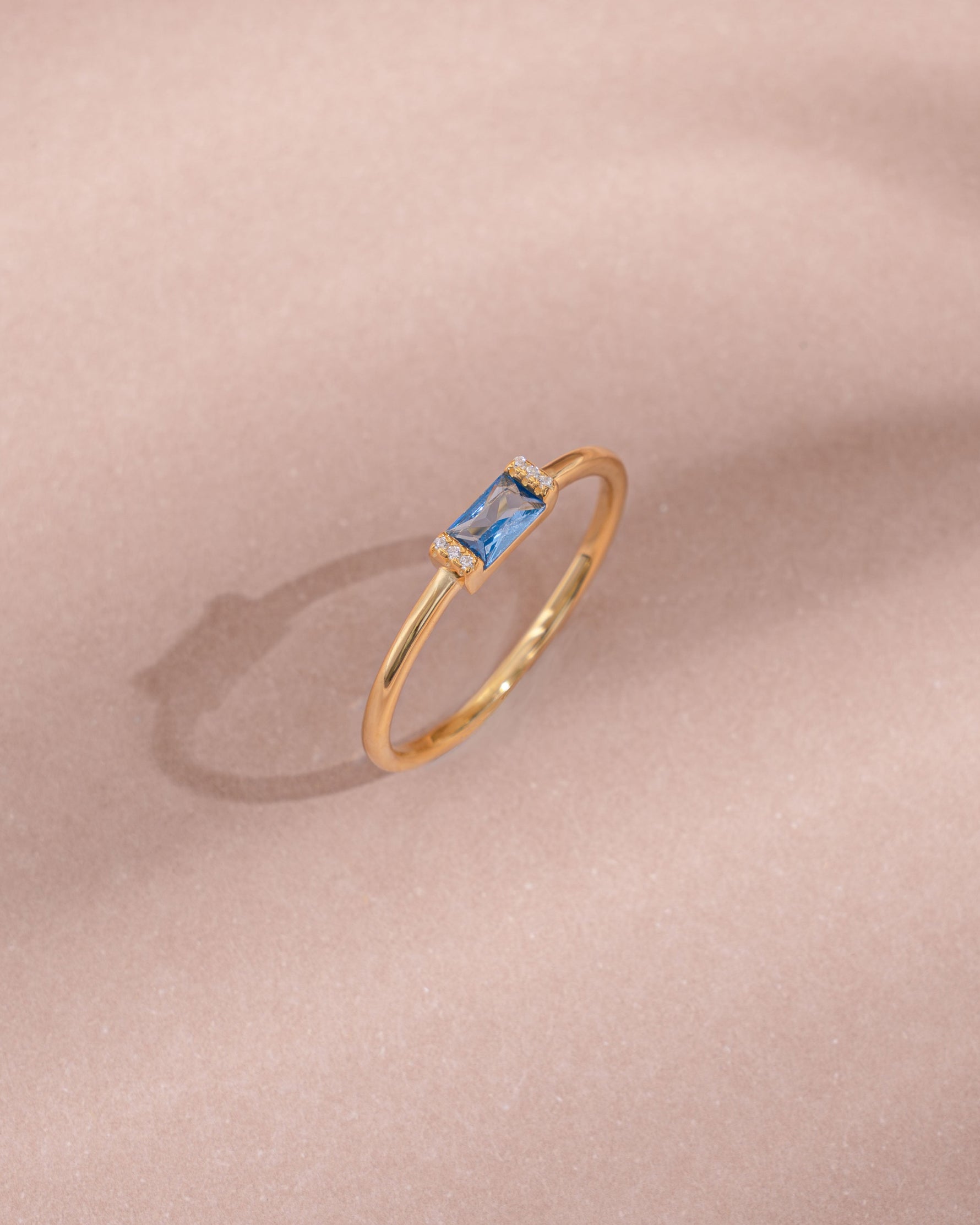 Gold aquamarine baguette ring with diamond accents, close-up view showcasing elegant design and sparkling gemstones.